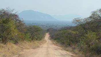 View down a dirt road of a mountain in the distance