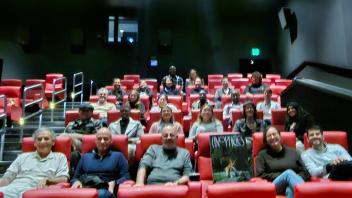 A movie theater half full of smiling people. The photo is slightly blurry.