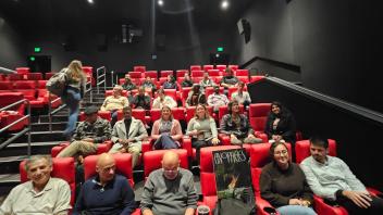 A movie theater half full of people. One person actively climbing the stairs.