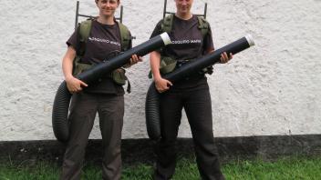 Two women wearing "mosquito mafia" t-shirts hold backpack aspirators