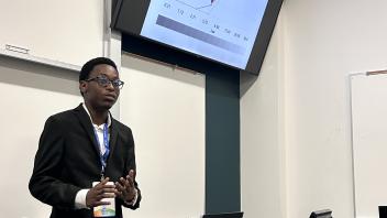 An undergraduate presents a powerpoint presentation from the front of a classroom.