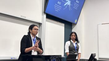 Two undergraduates present a powerpoint presentation from the front of a classroom.