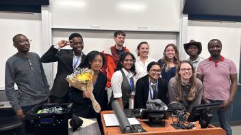A whole group of people gathered for a photo together in the front of a classroom