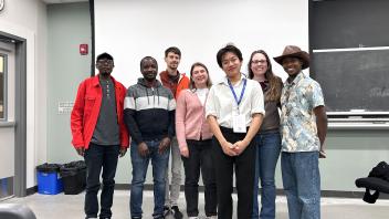 A whole group of people gathered for a photo together in the front of a classroom