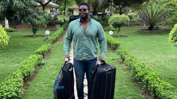 A man stands in a walkway with two suitcases