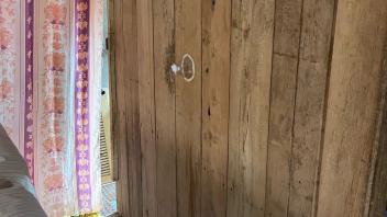 Three cones are tacked to a wooden wall with cotton plugs in their small ends. The cones are positioned diagonally on the wall so that they are several feet apart in both height and width.